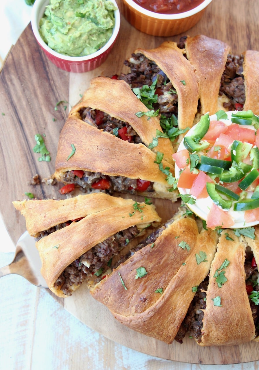 Taco ring made with Pillsbury crescent roll dough, filled with taco seasoned ground beef, with slice cut out