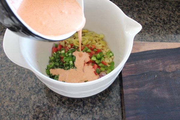 creamy dressing poured over diced vegetables in a large bowl