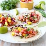 Chipotle honey glazed salmon is placed in warm corn tortillas & topped with fresh mango salsa in this mouth-watering recipe for healthy salmon tacos!