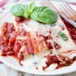Cheese manicotti on plate with marinara sauce and fresh basil