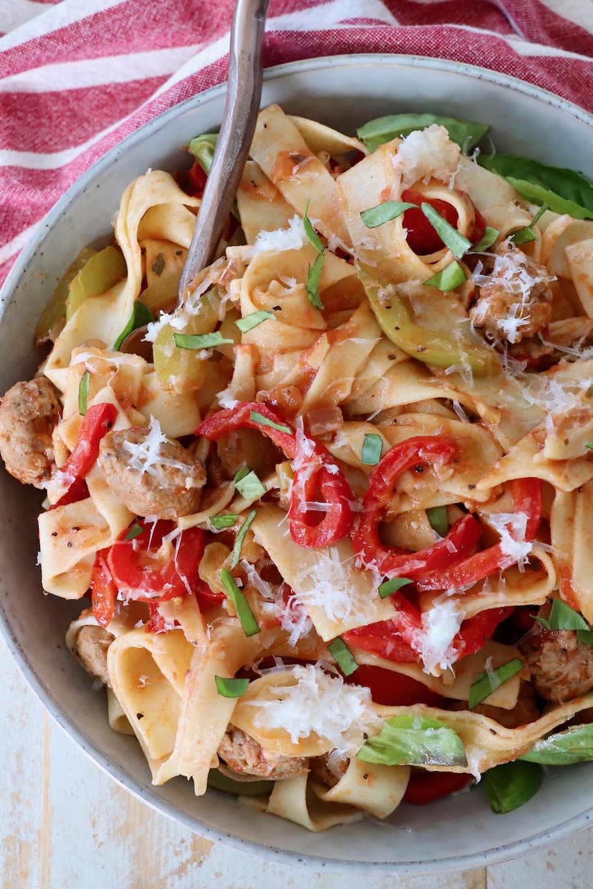cooked pasta noodles tossed with peppers and sausage in bowl with fork