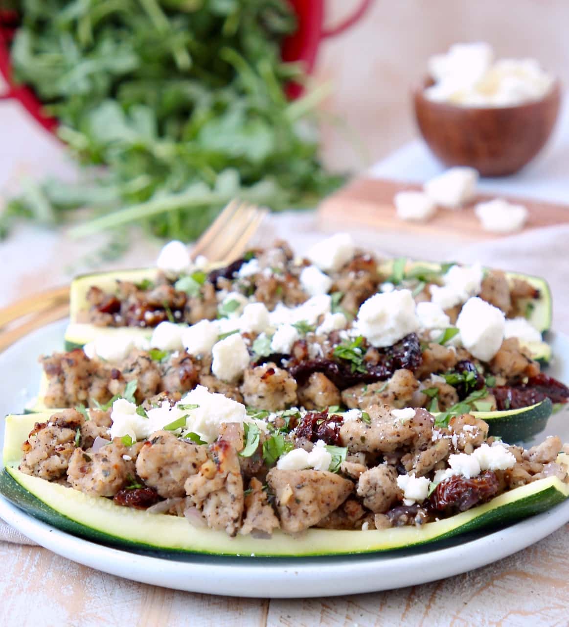 Ground Turkey, Sun Dried Tomato and Feta Cheese in hollowed zucchini halves on white plate