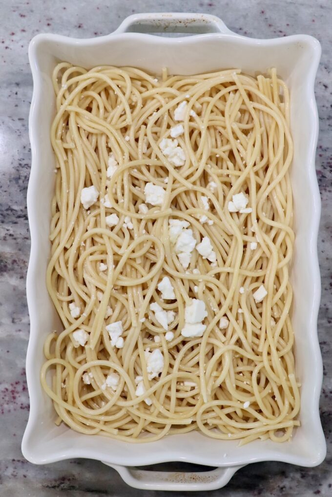 cooked pasta noodles in casserole dish with feta cheese crumbles
