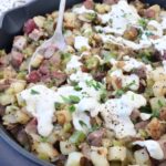 steak and potato hash in skillet topped with cheese sauce
