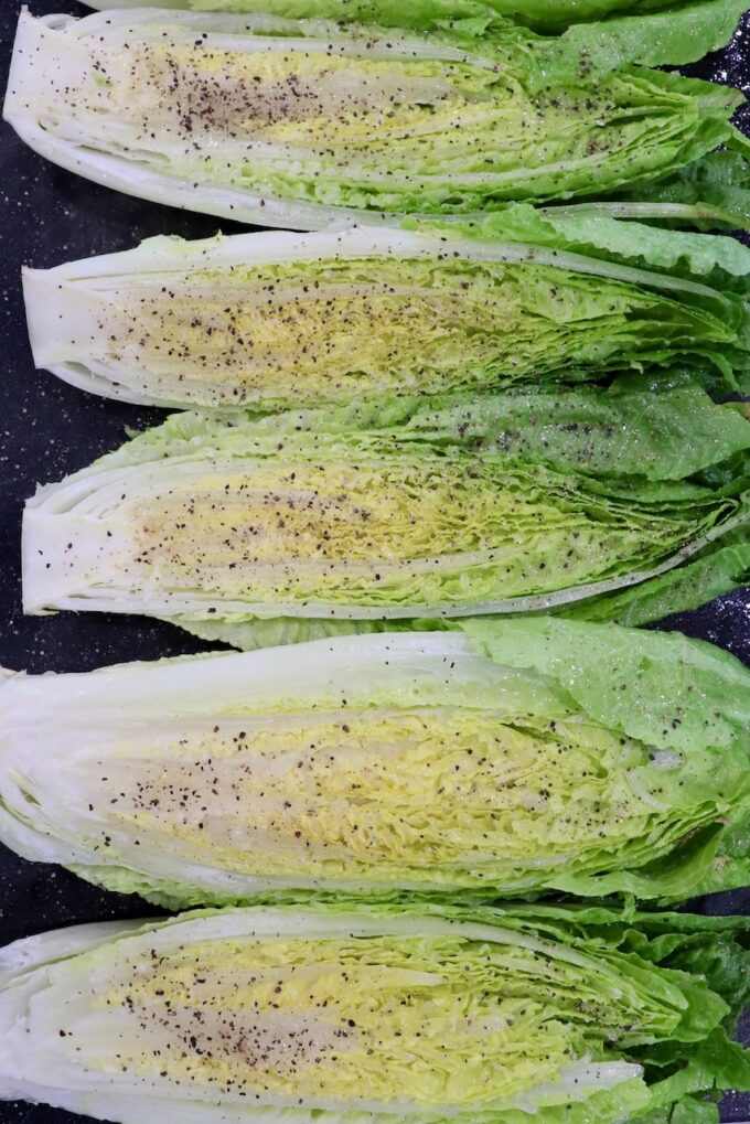 seasoned romaine lettuce hearts cut in half and seasoned on cutting board