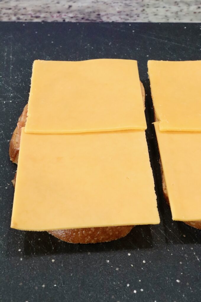 slices of cheddar cheese placed on two slices of bread on a cutting board
